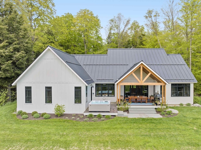 back of property with a standing seam roof, outdoor lounge area, a lawn, and board and batten siding