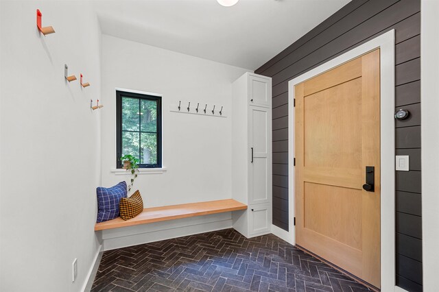 mudroom featuring brick floors and baseboards