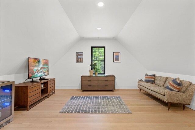 living area with light wood finished floors, vaulted ceiling, wine cooler, baseboards, and recessed lighting