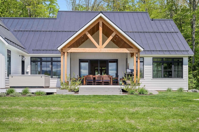 rear view of house with a standing seam roof, metal roof, and a lawn