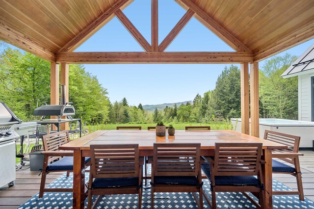 view of patio / terrace with a hot tub, outdoor dining area, and a deck with mountain view