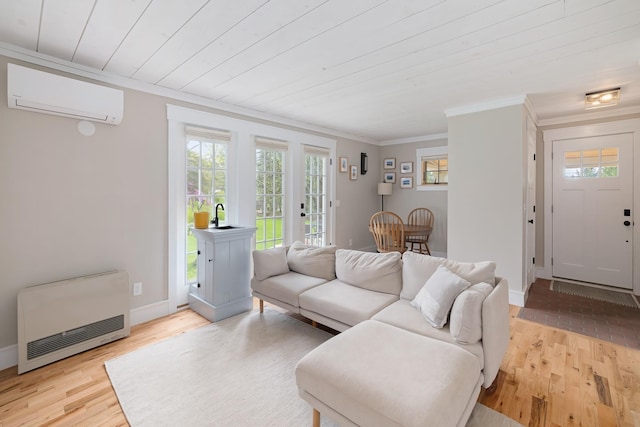 living room with heating unit, a wall mounted AC, crown molding, light wood finished floors, and baseboards