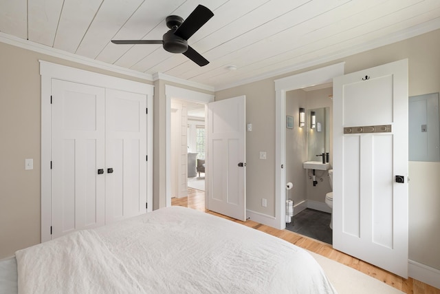 bedroom with light wood finished floors, ornamental molding, a closet, connected bathroom, and ceiling fan