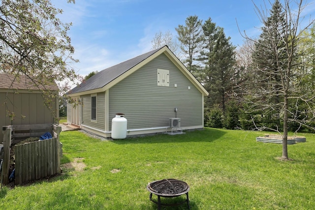 view of side of home featuring a yard, an outdoor fire pit, and an outbuilding