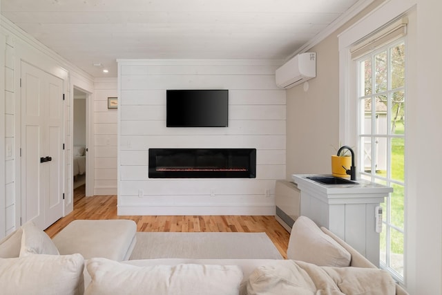 living area featuring a wall unit AC, crown molding, a glass covered fireplace, wood finished floors, and recessed lighting