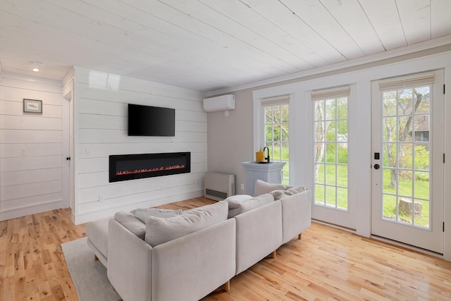 living area featuring healthy amount of natural light, a glass covered fireplace, light wood-type flooring, wood ceiling, and a wall mounted air conditioner