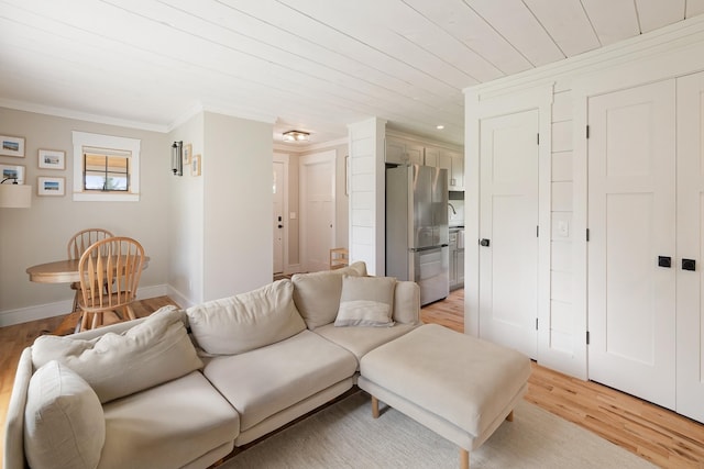 living room with light wood-style floors, crown molding, and baseboards