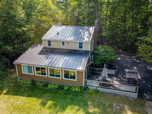 111 Shore Dr, Henniker, NH 03242 - back of house with a standing seam roof, metal roof, a wooden deck, a lawn, and a view of trees