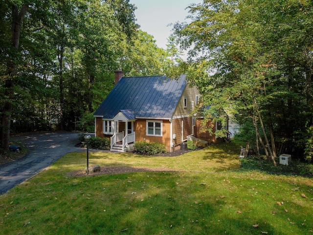 111 Shore Dr, Henniker, NH 03242 - view of front facade featuring a chimney, metal roof, a front lawn, and asphalt driveway