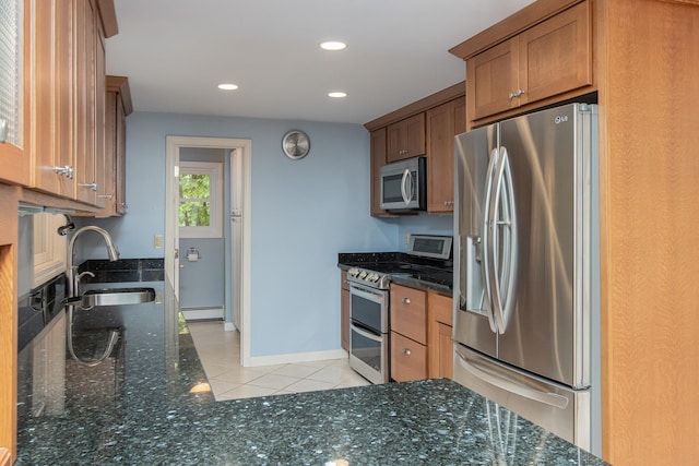 111 Shore Dr, Henniker, NH 03242 - kitchen with appliances with stainless steel finishes, a baseboard heating unit, light tile patterned floors, a sink, and dark stone countertops
