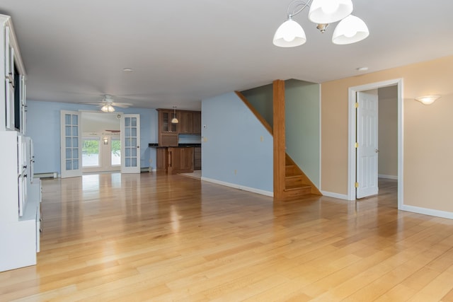 111 Shore Dr, Henniker, NH 03242 - unfurnished living room with stairs, a chandelier, light wood finished floors, a ceiling fan, and baseboards