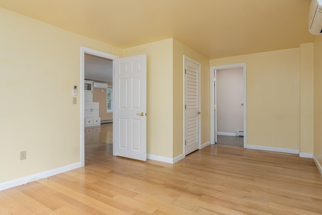111 Shore Dr, Henniker, NH 03242 - empty room featuring light wood-style flooring, baseboards, a wall mounted AC, and a baseboard radiator