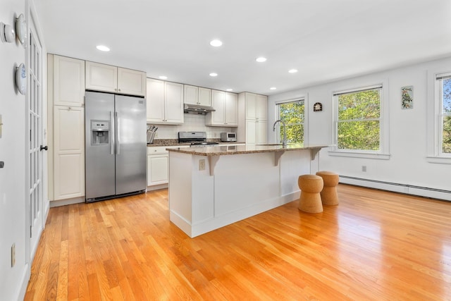 4 Oleary Ave, Hanover, NH 03755 - kitchen with appliances with stainless steel finishes, under cabinet range hood, light wood-style flooring, a sink, and a breakfast bar area