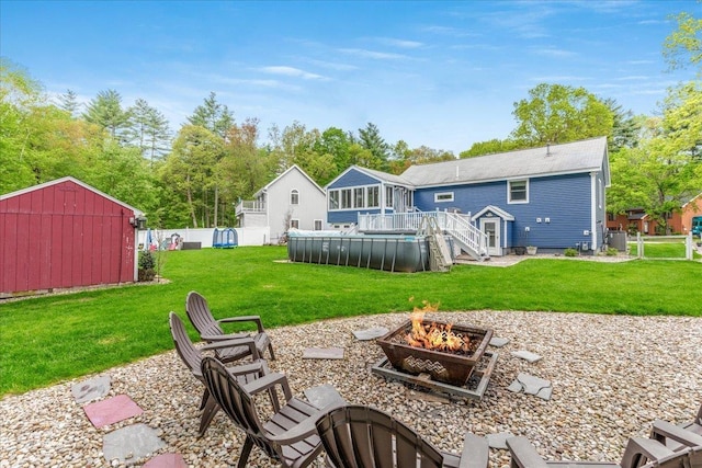 8 Bowman Ct, Merrimack, NH 03054 - view of green lawn with a fire pit, an outdoor pool, a wooden deck, and an outdoor structure