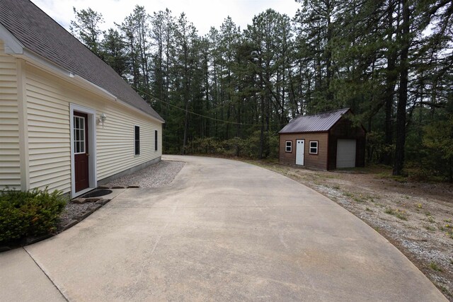 334 Silver Pine Ln, Tamworth, NH 03886 - view of patio / terrace featuring an outbuilding, a garage, and a wooded view