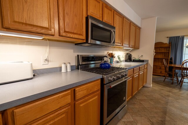 334 Silver Pine Ln, Tamworth, NH 03886 - kitchen featuring appliances with stainless steel finishes, brown cabinetry, dark countertops, and stone finish floors