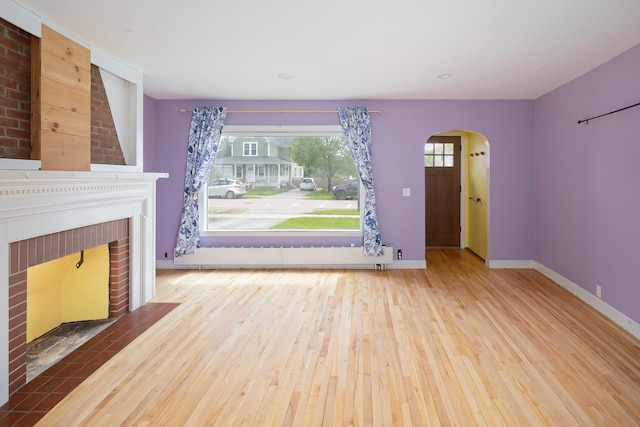 14 Butler St, Waterbury, VT 05676 - unfurnished living room with arched walkways, wood finished floors, a brick fireplace, baseboards, and recessed lighting
