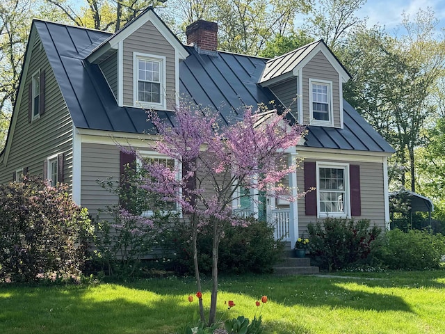 cape cod-style house featuring a standing seam roof, metal roof, a chimney, and a front yard