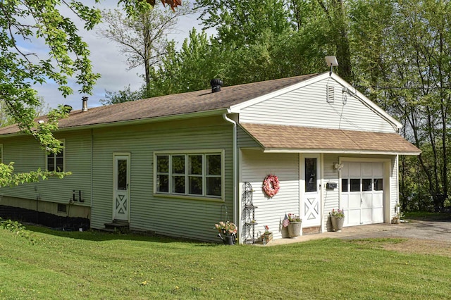 view of front of house featuring entry steps, roof with shingles, a front yard, and asphalt driveway