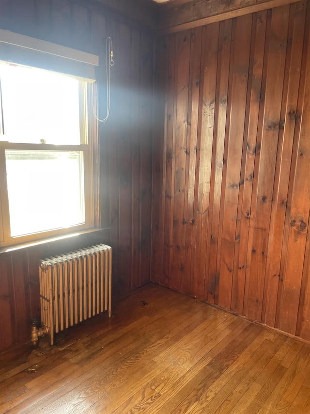 102 Chestnut Hill Rd, Rochester, NH 03867 - empty room with radiator, hardwood / wood-style flooring, plenty of natural light, and wooden walls