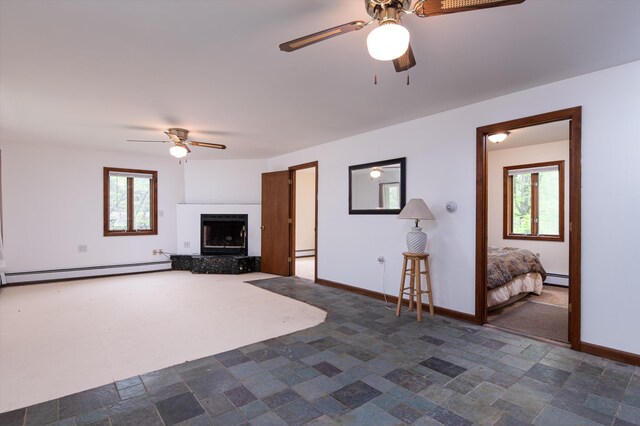 143 Okemo Acres, Ludlow, VT 05149 - unfurnished living room featuring a ceiling fan, a baseboard radiator, plenty of natural light, and a fireplace with raised hearth
