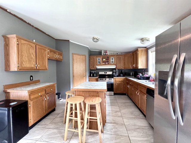 kitchen featuring appliances with stainless steel finishes, light countertops, a kitchen island, under cabinet range hood, and crown molding