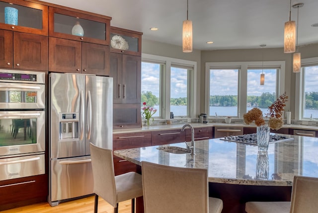 25 N Shore Rd, Windham, NH 03087 - kitchen with appliances with stainless steel finishes, a sink, a warming drawer, a breakfast bar area, and light stone counters