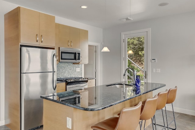25 N Shore Rd, Windham, NH 03087 - kitchen with stainless steel appliances, a sink, tasteful backsplash, dark stone counters, and a center island with sink