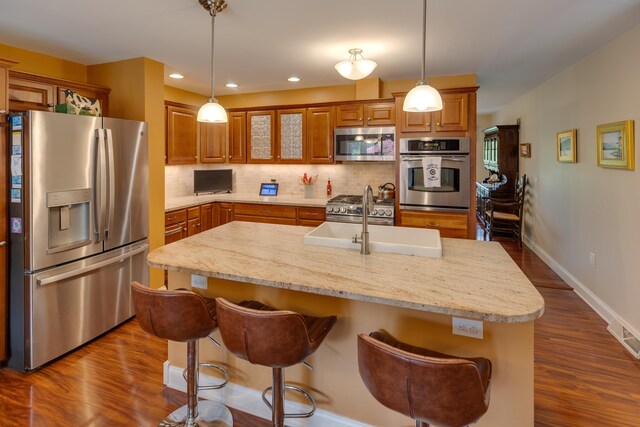 104 Champagne Cir, Campton, NH 03223 - kitchen with stainless steel appliances, brown cabinetry, a breakfast bar area, backsplash, and dark wood-type flooring