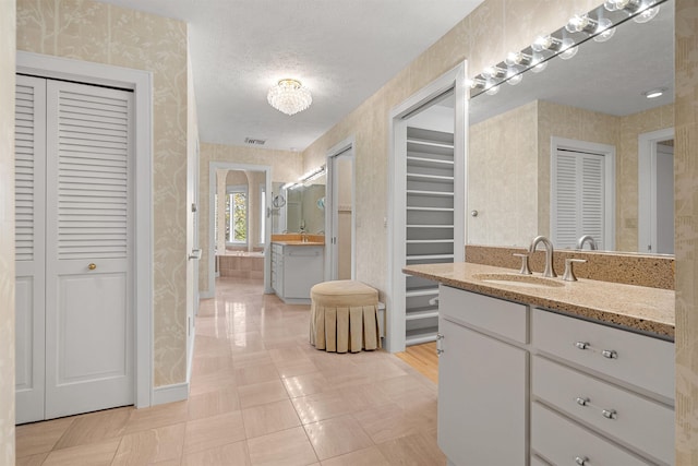 43 Sterling Pl, Bow, NH 03304 - bathroom featuring a closet, wallpapered walls, vanity, a textured ceiling, and baseboards