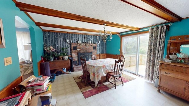 1862 Hooksett Rd, Hooksett, NH 03106 - dining area featuring beam ceiling, a brick fireplace, a textured ceiling, arched walkways, and a chandelier