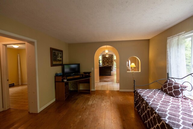 11 Henry Dr, Effingham, NH 03882 - bedroom with hardwood / wood-style flooring, arched walkways, baseboards, a textured ceiling, and baseboard heating