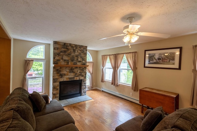 11 Henry Dr, Effingham, NH 03882 - living area with baseboard heating, a textured ceiling, a fireplace, light wood-style flooring, and a ceiling fan