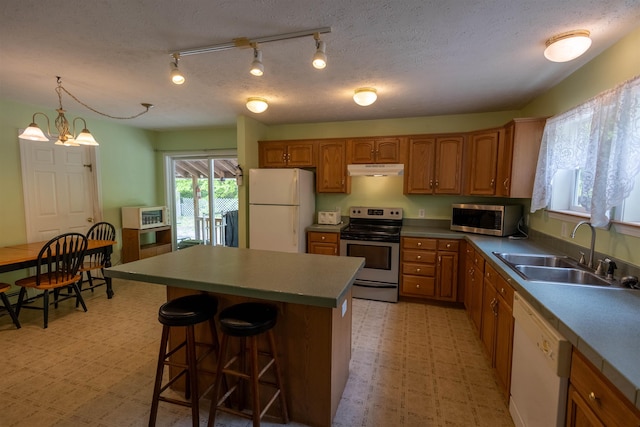 11 Henry Dr, Effingham, NH 03882 - kitchen with appliances with stainless steel finishes, a sink, under cabinet range hood, brown cabinetry, and light flooring