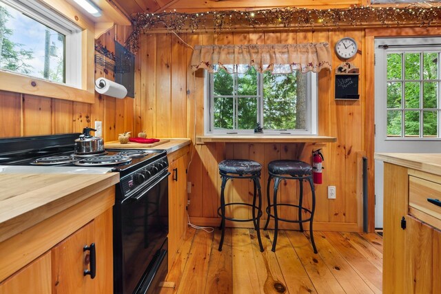 239 NE Pond Rd, Milton, NH 03851 - kitchen featuring black electric range oven, butcher block countertops, wooden walls, plenty of natural light, and light wood finished floors
