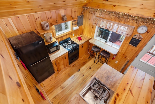 239 NE Pond Rd, Milton, NH 03851 - kitchen featuring black appliances, wooden walls, light wood-style floors, electric panel, and butcher block counters