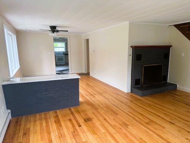 54 E Center St, Rutland City, VT 05701 - unfurnished living room with a baseboard heating unit, a fireplace, light wood-type flooring, a ceiling fan, and crown molding