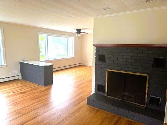 54 E Center St, Rutland City, VT 05701 - unfurnished living room featuring baseboard heating, a fireplace, healthy amount of natural light, and ornamental molding