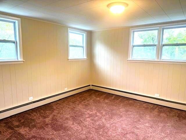 54 E Center St, Rutland City, VT 05701 - spare room featuring carpet floors, plenty of natural light, a baseboard heating unit, and wood walls