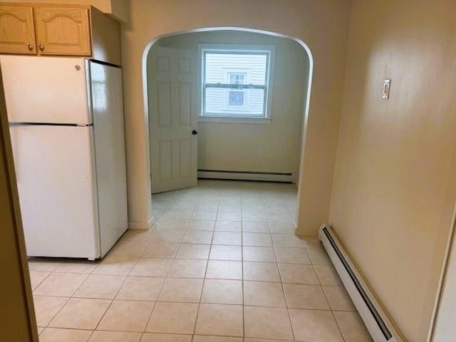 54 E Center St, Rutland City, VT 05701 - kitchen featuring freestanding refrigerator, a baseboard heating unit, a baseboard radiator, light tile patterned flooring, and arched walkways
