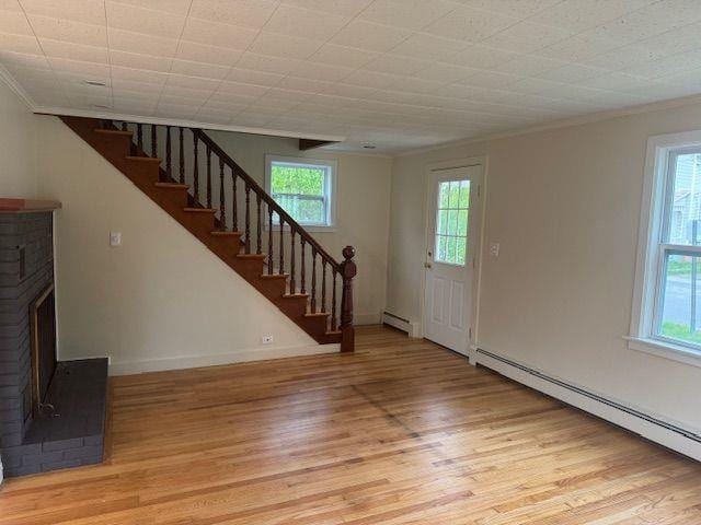 54 E Center St, Rutland City, VT 05701 - entryway featuring a baseboard radiator, ornamental molding, light wood finished floors, stairs, and a brick fireplace