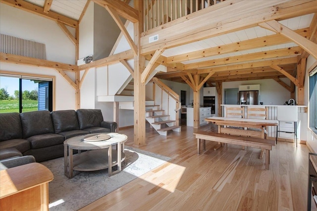 64 Atkins Farm Rd, Ferrisburgh, VT 05456 - living area featuring beam ceiling, stairs, wood finished floors, and high vaulted ceiling