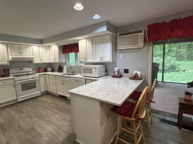 7 Juniper Ridge Rd, Exeter, NH 03833 - kitchen featuring white appliances, a sink, under cabinet range hood, a peninsula, and a wall mounted air conditioner