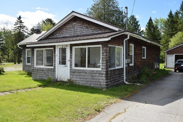 18 Bridge St, Lancaster, NH 03584 - view of front of house with an outdoor structure, a front yard, metal roof, a chimney, and a standing seam roof