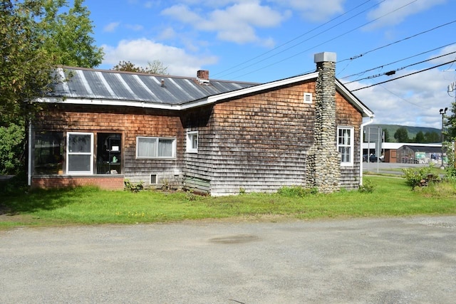 18 Bridge St, Lancaster, NH 03584 - view of front facade with a chimney, a front yard, and metal roof