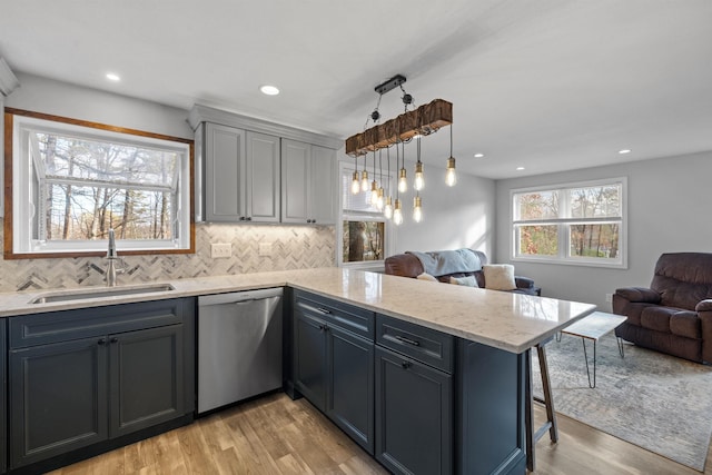 21 Regis Rd, Laconia, NH 03246 - kitchen featuring stainless steel dishwasher, a sink, open floor plan, a peninsula, and light wood-style flooring