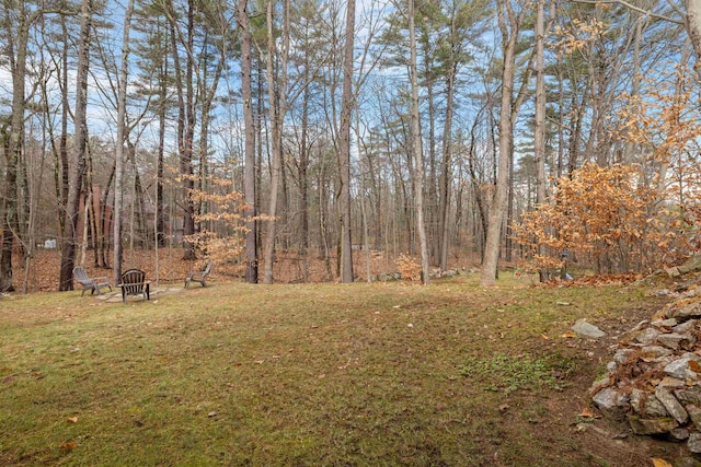 21 Regis Rd, Laconia, NH 03246 - view of grassy yard featuring an outdoor fire pit and a wooded view