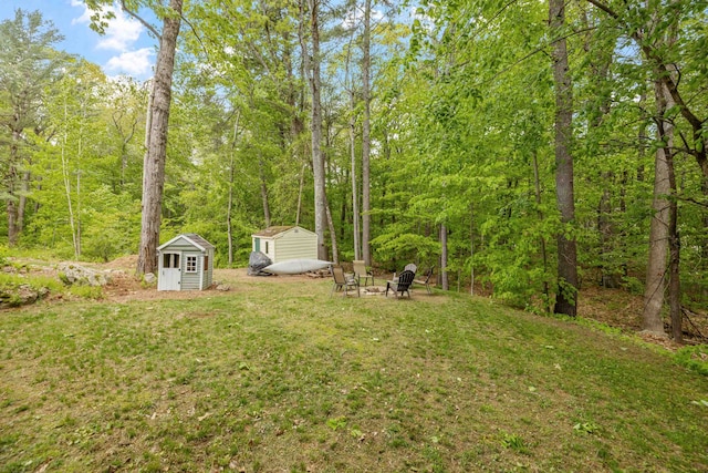 21 Regis Rd, Laconia, NH 03246 - view of grassy yard with an outdoor fire pit and a wooded view