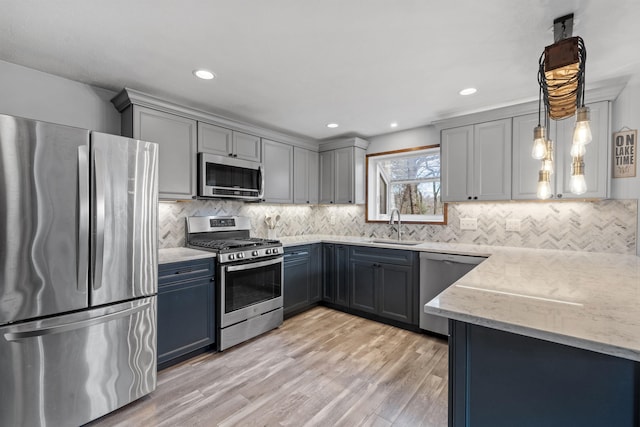 21 Regis Rd, Laconia, NH 03246 - kitchen with appliances with stainless steel finishes, a sink, light stone counters, light wood-type flooring, and decorative backsplash