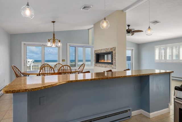 185 Kings Hwy, Hampton, NH 03842 - kitchen with lofted ceiling, light tile patterned floors, a stone fireplace, a baseboard heating unit, and dark stone counters